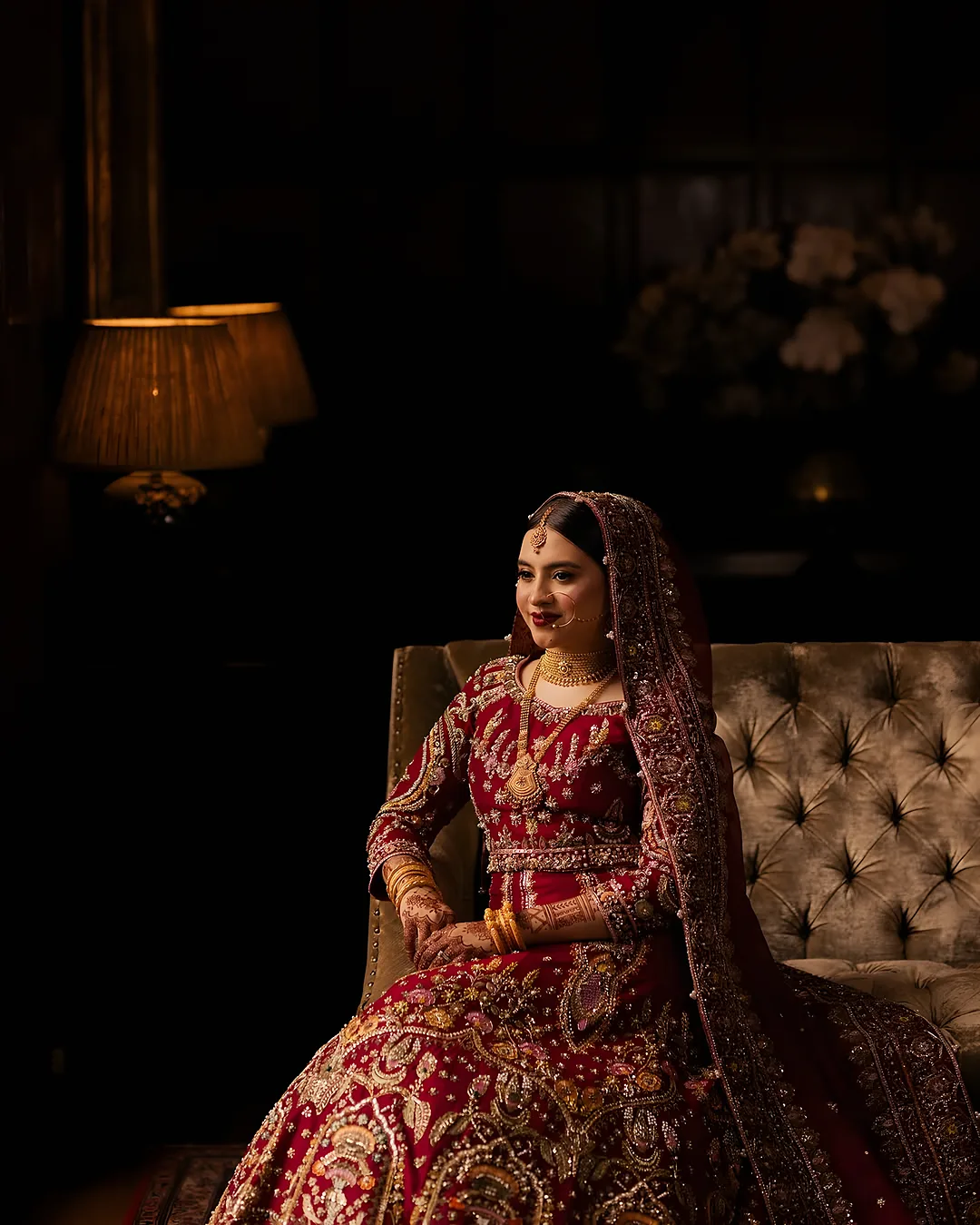 Bride in a red lehenga seated in a candlelit room